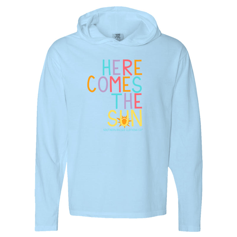Long-sleeve blue hoodie with slogan "Here Comes the Sun."  Each letter rotates in color, blue, purple, pink, cantaloupe. The word Sun is in all yellow with graphic of orange sun.