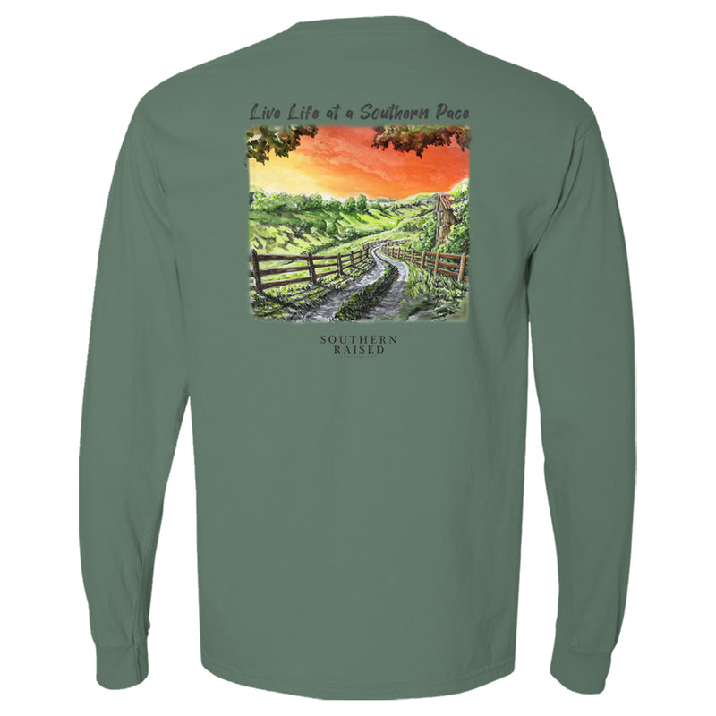 Southern t shirt slogan is "Live Life at a Southern Pace" and scene is winding country road in a field at sunset. Comfort Color tee is light green.
